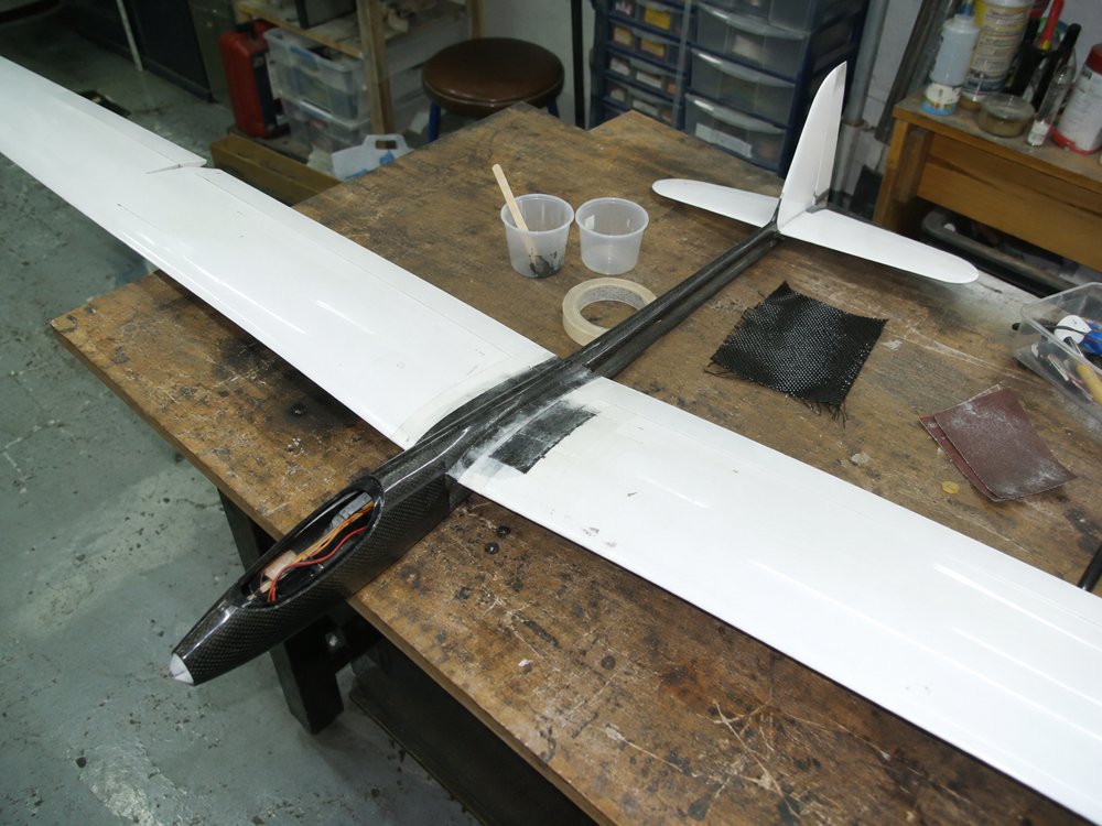 Illustration of a carbon-fibre fixed-wing RC glider on a repair bench